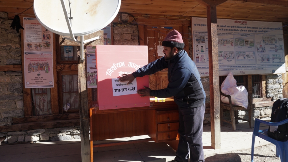 a man with red cap is pasting the poster in voting box